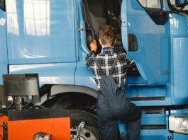 Mechanik w roboczym stroju sprawdza ciężarówkę w warsztacie