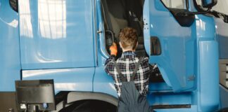 Mechanik w roboczym stroju sprawdza ciężarówkę w warsztacie