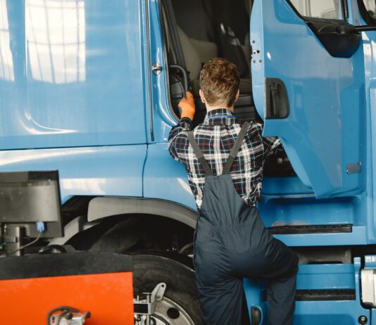 Mechanik w roboczym stroju sprawdza ciężarówkę w warsztacie