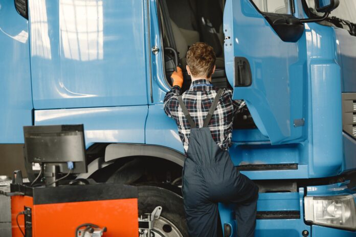 Mechanik w roboczym stroju sprawdza ciężarówkę w warsztacie